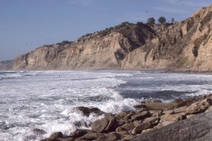 Black's Beach iconic coastal cliffs that contain sediment gravity flow deposits (mainly turbidites and debris flows), and the remnants of an Eocene submarine canyon. This view is north of Scripps Pier, California.