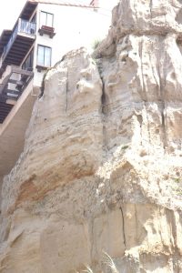 Typical channel conglomerates eroding into thick (proximal) turbidites and thinner channel overbank facies, Black's Beach submarine canyon. Signs at the beach entrance warn of rock falls and house collapses.