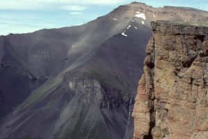 Panorama of a slope-shelfbreak gully-shelf-to fluvial transition, beautifully exposed at Mt Tsatia, Jurassic Bowser Basin, northern British Columbia. Conglomerate on the immediate right are equivalent to the rusty beds near the opposite summit. The shelfbreak is located at the top of the wedge-shaped gully (corresponds to the top of the waterfall) - below the gully are slope deposits. The thickness of strata in this view is more than a kilometre.