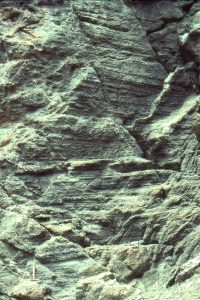 Well-developed layering in this debris flow, probably formed during a prolonged, quasi-continuous surging flow of grit to cobble sized clasts. The whole unit is about 8m thick. Hammer bottom left. Todagin submarine slope channel complex, Bowser Basin.