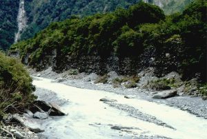 Incision of a Late Pleistocene (very humid) alluvial fan at Franz Joseph, New Zealand.  The gravels are very coarse; boulders up to 3m across. The sediment source is in the immediate background - the western edge of the Southern Alps (here, mostly greenschist).