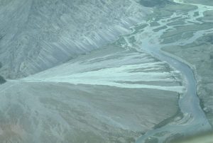 This small (humid) alluvial fan drains into Peel River, east Yukon. The fan's outer edge dips its toes in Peel River. Inactive segments of the fan are incised by the river, but active segments provide new gravel, sand and mud to active river side bars (river flow is to the top). Recently active fan channels and flooded swaths are mainly in the central part of the fan, having migrated from the fan edge farthest from the viewer.