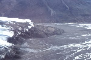 Part of the Strand Glacier terminal moraine, the meltwater, and outwash channels. Sediment on top of the glacier has been concentrated by ablation. The outwash channel in the foreground is fed by a subglacial stream. The sediment eventually finds its way to Strand Fiord as a fan delta.