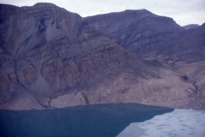 A thicker section of Permo-triassic shale intruded by several diabase dykes, in the hanging wall above Stolz Thrust, Buchanan Lake, Axel Heiberg Island. The paler brown units at lake level is the Eocene synorogenic Buchanan Lake Formation.