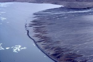 Typical Arctic fan deltas, Slidre Fiord. Braided stream supply to the delta front is clear, with the active channels regularly moving across the delta top. A gravel beach ridge formed along the inactive delta front, has become detached. Linear and arcuate cracks across the delta top are permafrost polygons.