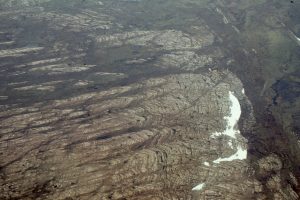 One of the more spectacular stromatolite buildups, or reefs, in the Proterozoic Mavor Formation, Belcher Group. The aerial view shows a transition from shallow subtidal, flat laminates to simple mounds, to large domes with 3-5m synoptic relief at the platform margin - slope deposits (Costello Fm) extend from the margin on the right. Smaller mounds on the left coalesce into larger mounds. Field of view along mound length is about 800m. Stratigraphic thickness is about 150m along this section of Tukarak Island.