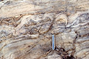 Dololutite beds deformed while in a plastic state, are interbedded with and truncated by undeformed crossbedded (dolomitic) grainstone.  These folds probably formed as packages of sediment were moved during karstification and limestone solution collapse. Some layers have detached from one another, forming voids that were eventually filled by aragonite-fibrous calcite - subsequently converted to dolomite. Both images from the Rowatt Fm, Belcher Islands, about 2 billion years old.