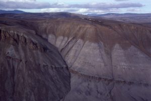 Syntectonic Buchanan Lake conglomerate (brown hues) overlies unconformably Triassic sandstone - resistant units within the Triassic are diabase dykes. The Eocene conglomerate was derived from an uplifted thrust panel farther west (left).  Stang Bay, Axel Heiberg Island.