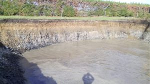 Thin sandy loam topsoil and iron-stained layer on coastal plain gravels. The upper part of the topsoil has been disturbed by cultivation. The normal position of the watertable is at the transition to gray gravel. Kaiua, Thames coast east of Auckland, NZ.