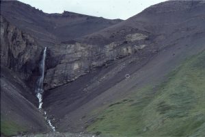 A shelfbreak gully, incised into slope deposits, overlain by cyclothemic, and progressively shallowing shelf facies. Gully fill is mostly conglomerate. It is thickest at the waterfall (about 40m). Initiation of gullies was by fluvial erosion during sea level lowstands, aided by slumping in inherently unstable slope deposits. The gullies delivered gravel and sand to the basin beyond the slope.  Upper Jurassic, Tsatia Mt, Bowser Basin, British Columbia.