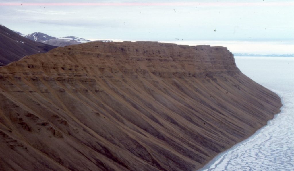 Talus fan colluvium sourced from bluffs of Eocene conglomerate (Buchanan Lake Fm.), Emma Fiord, Ellesmere Island. Depositional mechanisms are primarily mass wasting (rock fall and slide) and slope wash during the Arctic spring thaw. The transfer of colluvium to the shoreline will produce significant improvements in sorting and stratification. 