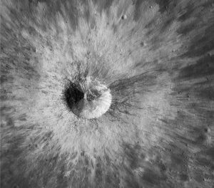 A relatively young crater, 1.8 km in diameter with well-preserved raised rim and a ray-like ejecta blanket. It is located in the partly buried and older crater Hedin. Smaller impact structures are also visible beneath the ejecta. The regolith surrounding this structure is a good example of impact gardening, likely composed of material derived from multiple impacts. Image Credit: NASA/GSFC/Arizona State University 2018 Lunar Reconnaissance Orbiter.